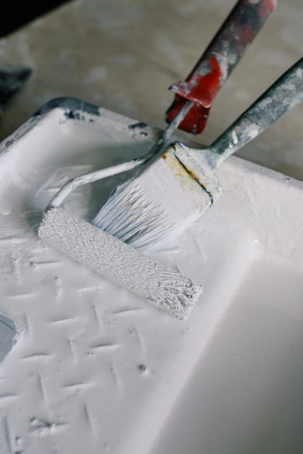 Roller and brush ready in a paint tray